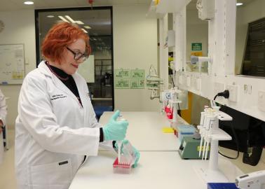 Professor Leonie Quinn, a woman with red hair and a lab coat, working in a laboratory